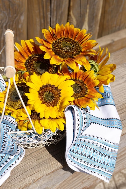 Beautiful sunflowers with napkin in basket on bench outdoors