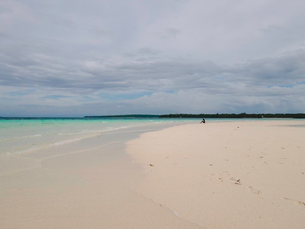 Beautiful sunny day on a calm pristine beach with grey skies in Indonesia