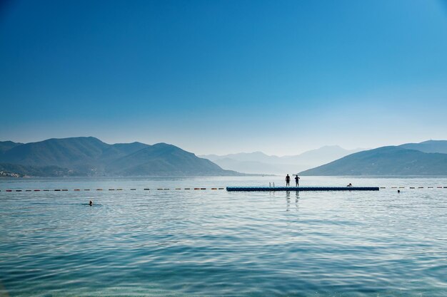 Beautiful sunny view of the bay of Kotor with a pontoon for swimming people in the sea