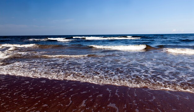 Прекрасная солнечная погода на побережье Балтийского моря, холодная летняя погода на побережье Балтийского моря, морской пейзаж в солнечный день с голубым небом и множеством волн на воде