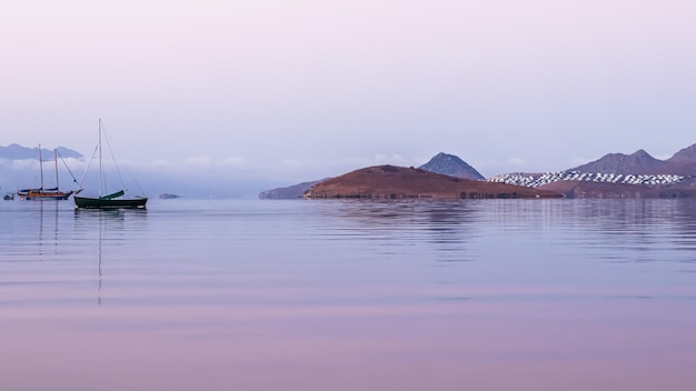 Красивый восход солнца на Эгейском море с островами, горами и лодками. Фото высокого качества