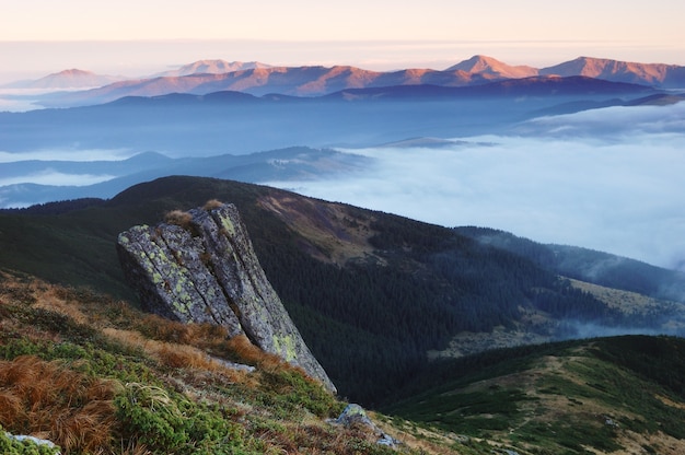 山の美しい日の出。朝日が昇る光の中で朝霧と山脈と秋の風景