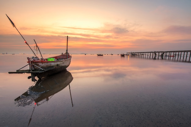 Beautiful sunrise over an old wooden fishing boat on thailand beach