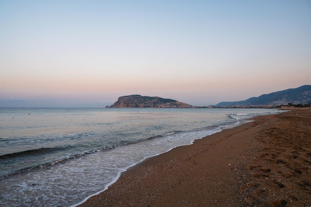 Foto bella scena dell'alba sulla spiaggia di alanya con vista sulla famosa isola di alanya in turchia