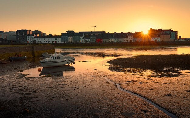 Beautiful sunrise scenery of colorful houses and boat reflected in corrib river at claddagh galway