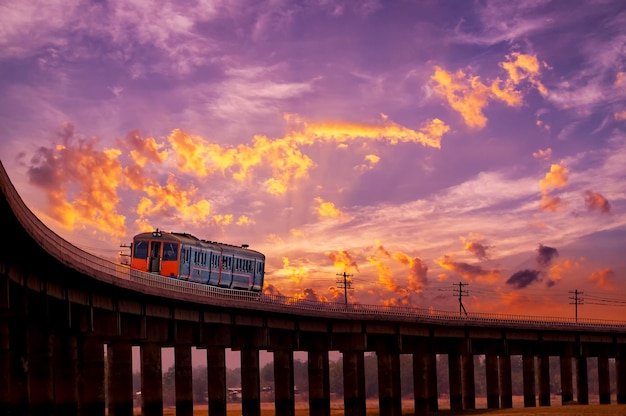 Foto bellissimo cielo all'alba o al tramonto sul treno che si muove sul ponte ferroviario in thailandia