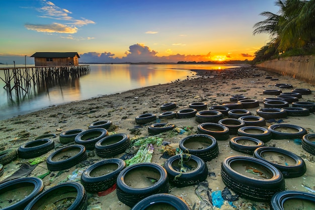 beautiful sunrise with old tires along the beach