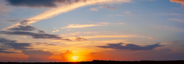 Beautiful sunset against the blue sky and strips of dark forest. The concept of space.