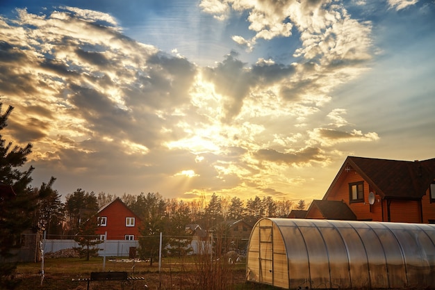 Фото Красивый закат и облака с солнечными лучами вечером над небольшим деревенским домом.