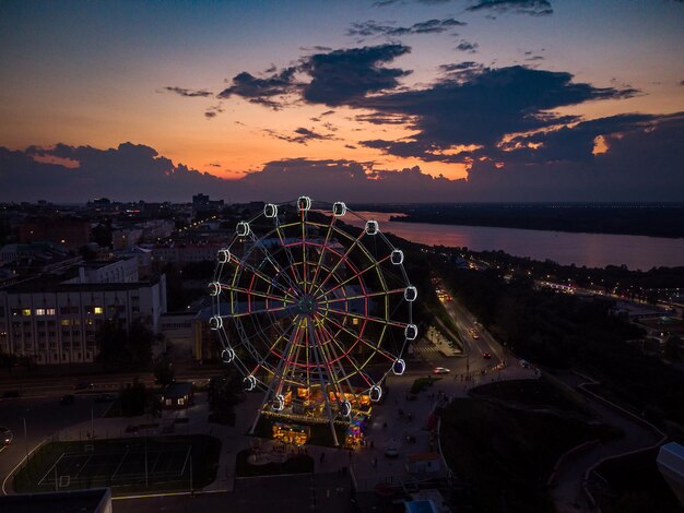 Foto bellissimo tramonto sulla città con una ruota gigante illuminata paesaggio urbano dall'alto