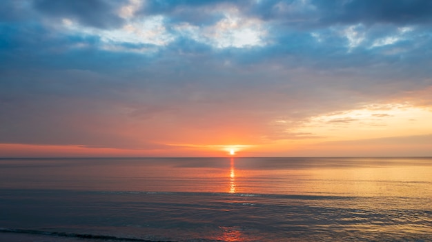 Beautiful sunset over the clam sea with cloud sky background Sunset over tropical beach Nature summer  concept Peak sunset over sea with yellow light reflect on sea water