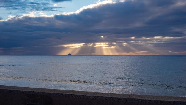 Beautiful sunset from the beach sunrays from the clouds boat at\
the horizon canary islands