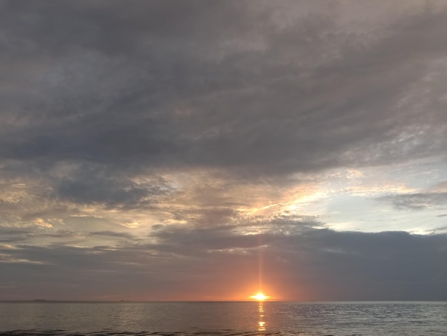 写真 曇り空の下、海に沈む美しい夕日