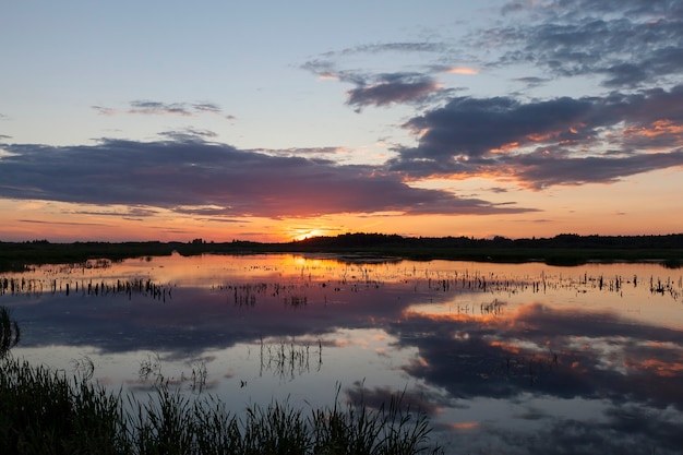 Bel tramonto sul lago nell'acqua che riflette il cielo colorato, paesaggio autunnale