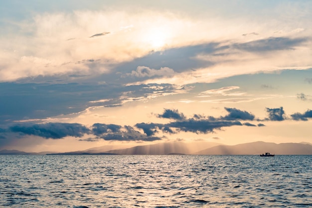 空の雄大な雲に反射する海に沈む美しい夕日