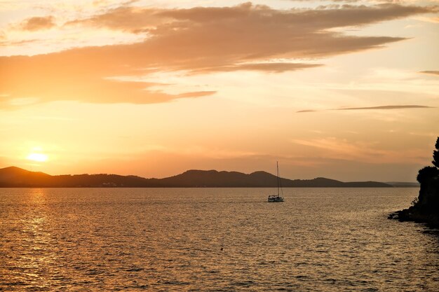 Foto bellissimo tramonto sul mare con una barca a vela in primo piano