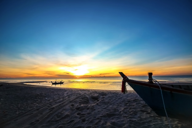 Beautiful sunset sunrise on the beach with silhouette boat