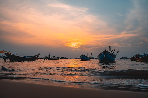 曇りの砂浜でボートと美しい夕日の熱帯の海の景色