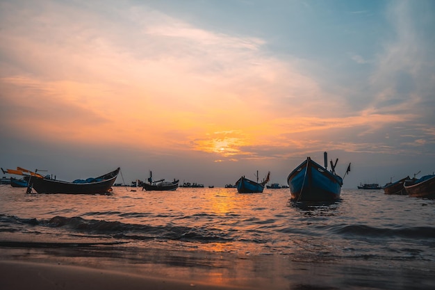 曇りの砂浜でボートと美しい夕日の熱帯の海の景色