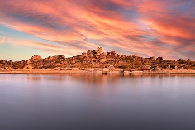 Beautiful sunset with orange sky on the shore of a lake