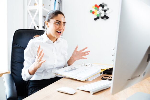 Beautiful surprised businesswoman looking at laptop while sitting at the office desk