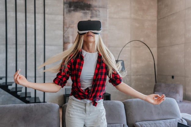Beautiful Swedish girl in plaid shirt and white pants using vr glasses at home Relaxing caucasian gi