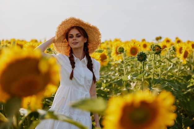 Beautiful sweet girl in a straw hat in a white dress a field of sunflowers agriculture unaltered High quality photo