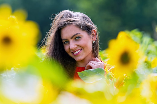 Beautiful sweet sexy woaman in a red sweater in a field of sunflowers at sunny day