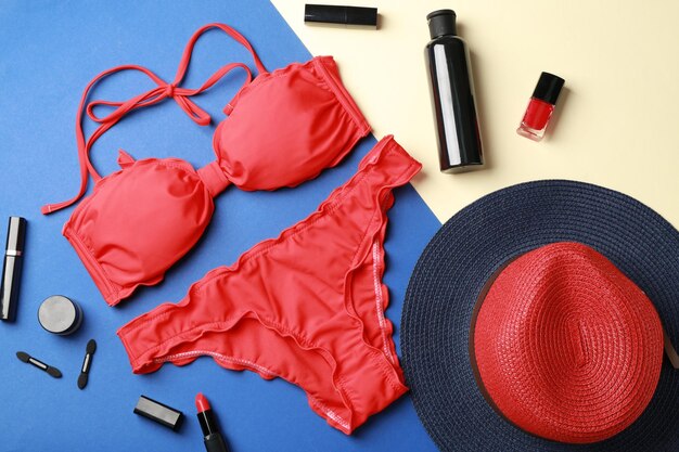 Photo beautiful swimsuit hat and different cosmetics on color background