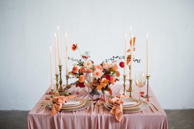 Красивая сервировка стола с осенними цветами, оранжевыми и розовыми салфетками и горящими свечами Концепция осенней свадьбы