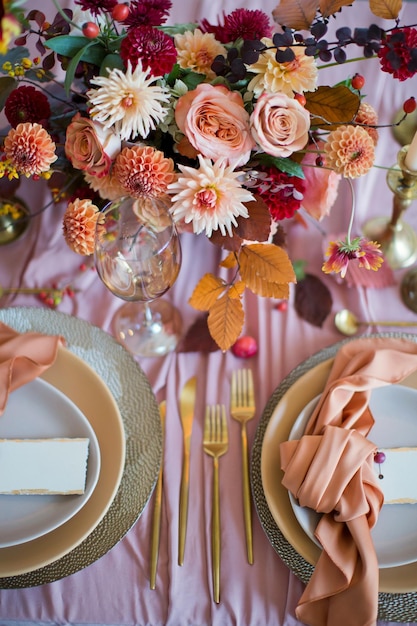 Beautiful table setting with autumn flowers orange and pink napkins and burning candles Autumn wedding concept