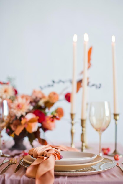 Beautiful table setting with autumn flowers orange and pink napkins and burning candles Autumn wedding concept