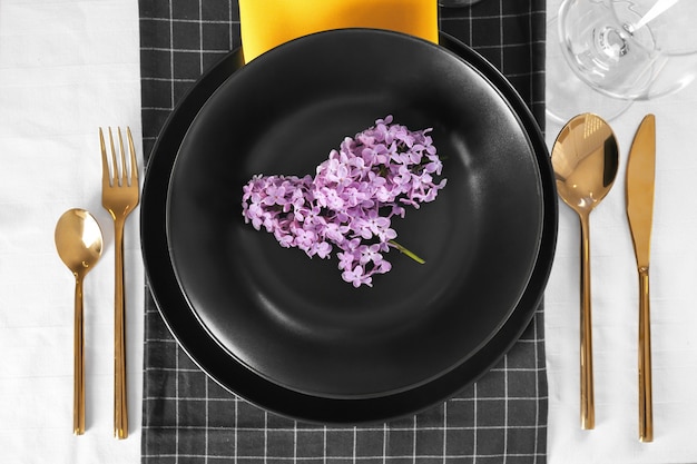 Beautiful table setting with lilac and golden cutlery