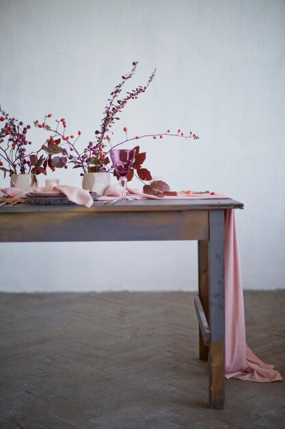 Beautiful table setting with pink napkins and pink runner golden forks and knives candles and autumn leaves and berries