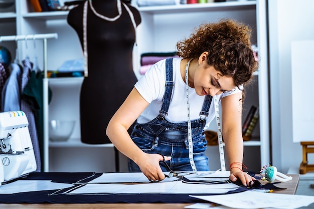 the beautiful tailor sews a dress on the table