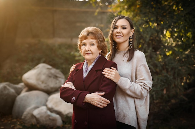 Beautiful tall daughter with her mother in the fall in the park among the trees