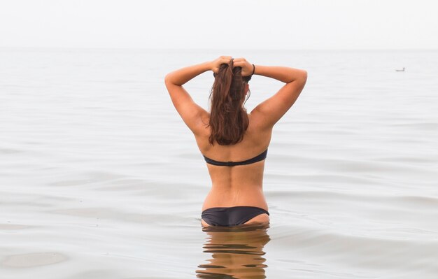 Foto bella ragazza abbronzata in spiaggia alla luce del sole