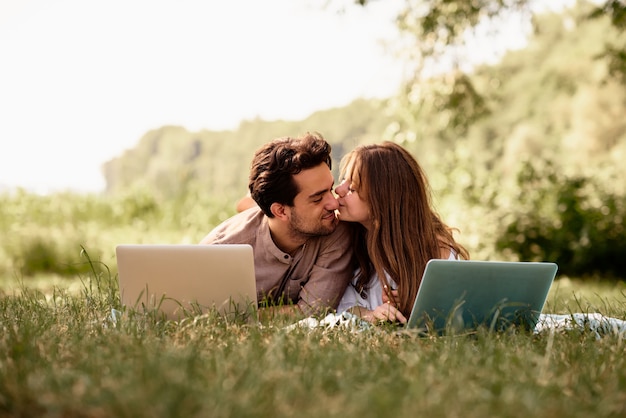 A beautiful teen couple man and women working use laptop to working at outdoor park holiday