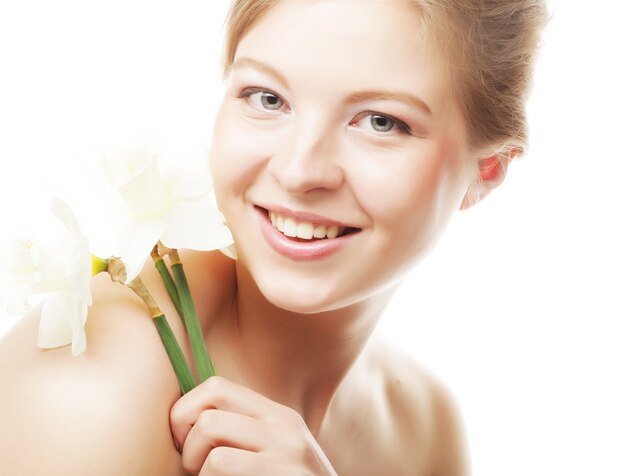 Beautiful teen girl smiling and with flower narcissus and looking at camera.