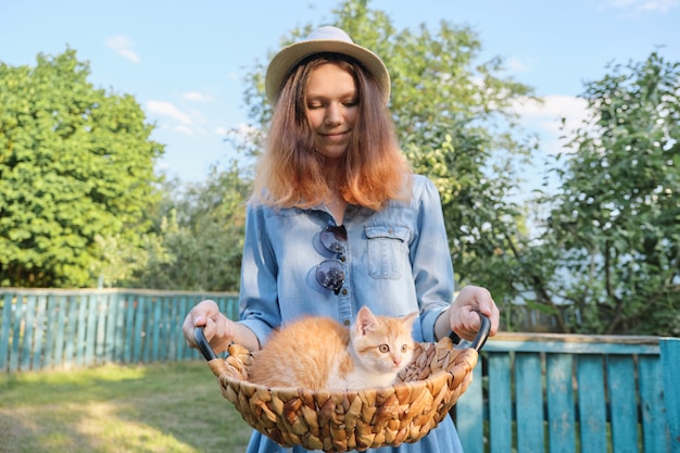 Beautiful teen girl with small red kitten in basket