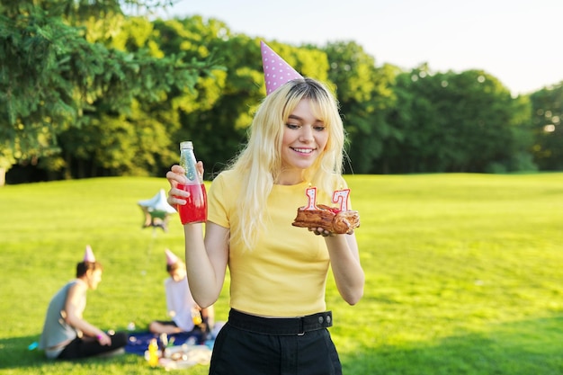 Beautiful teenage girl in a festiv hat on her birthday with a cake and candles