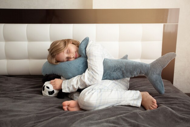 Beautiful teenage girl sleeping in bed with a soft toy