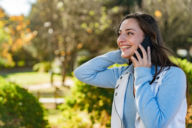 Bella ragazza adolescente che parla sul suo telefono cellulare in un parco