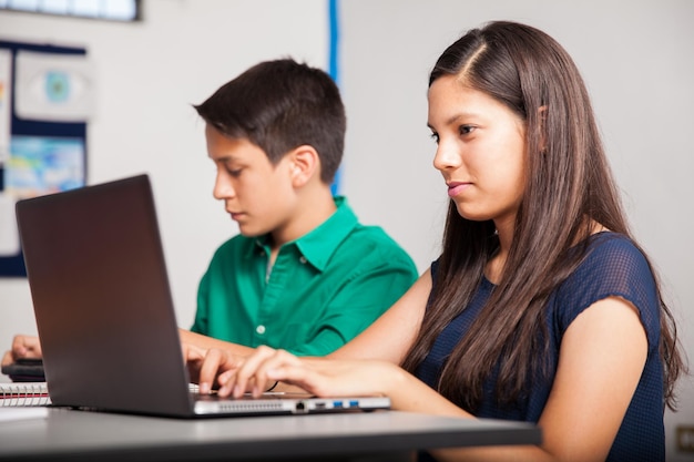 Beautiful teenage girl using a laptop computer at school