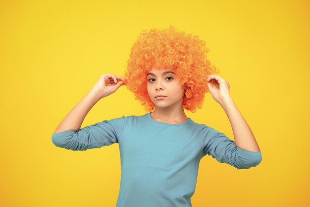 Photo beautiful teenage girl in wig isolated on yellow funny clown wig