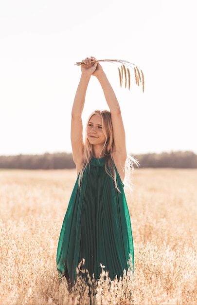 Beautiful teenage girl with long white hair walking through a wheat field on a sunny day