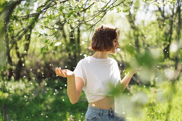 Beautiful teenage girl with spring flowers enjoying nature and laughing on spring garden Girl holding branch of an cherry tree Freedom and happiness concept Springtime