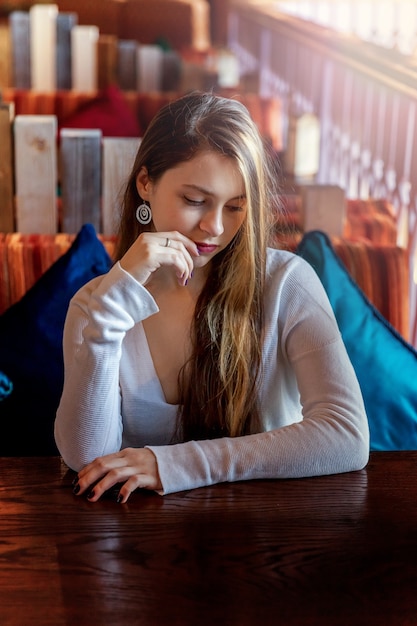 Beautiful teenage young smiling brunette girl sitting in cafe or bar at table