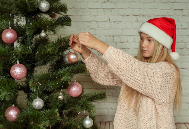 Beautiful teenager girl decorating Christmas tree at home