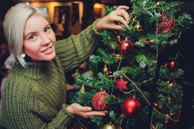 Bella ragazza dell'adolescente che decora l'albero di natale